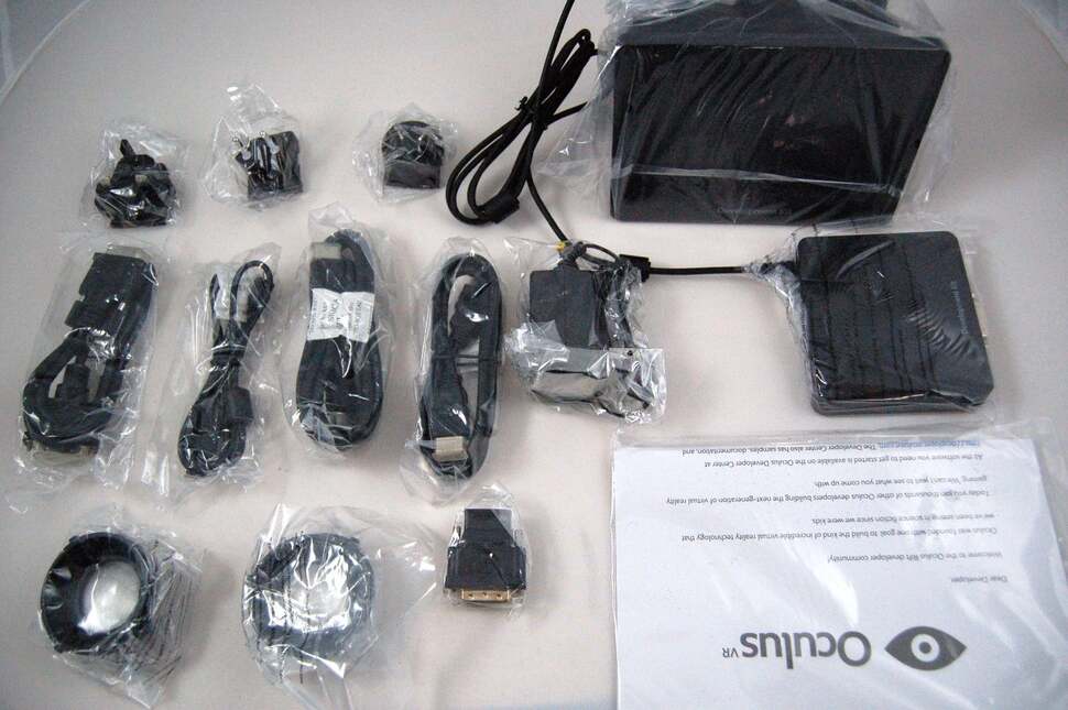 The full contents - PSU adaptors at the top, the Rift beside it. On the second row we find video cables, the PSU itself, then the breakout box. On the bottom we see the Rift lenses and an HDMI to DVI adaptor