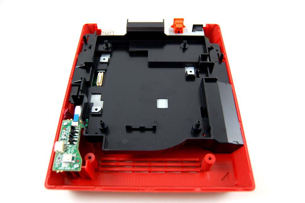 Going back to the chassis, we have a honking great piece of plastic to remove. Three metal tabs need to be pulled back here in order to get rid of it