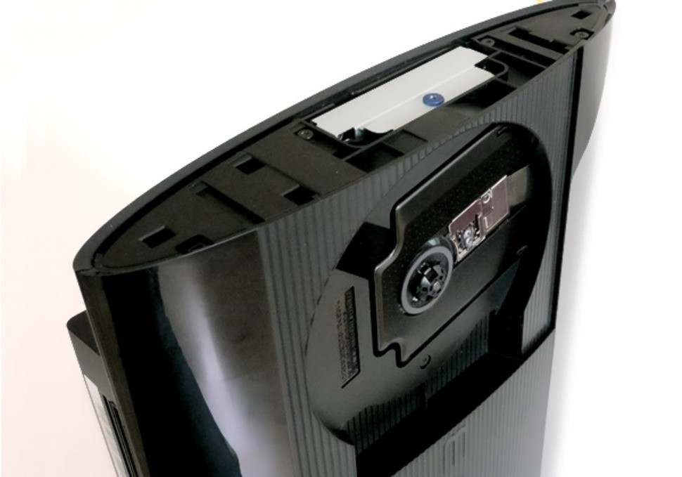 Prying open the top end of the casing reveals the hard drive bay, where we find a standard 5400rpm Hitachi hard drive - a Z5K500 HTS545050A7E380 model. It's a single platter 7mm drive but the bracket is large enough to support the more common 9.5mm units too. In this pic, we also see the new PS3 with the lid cover open, showing the recessed Blu-ray drive.